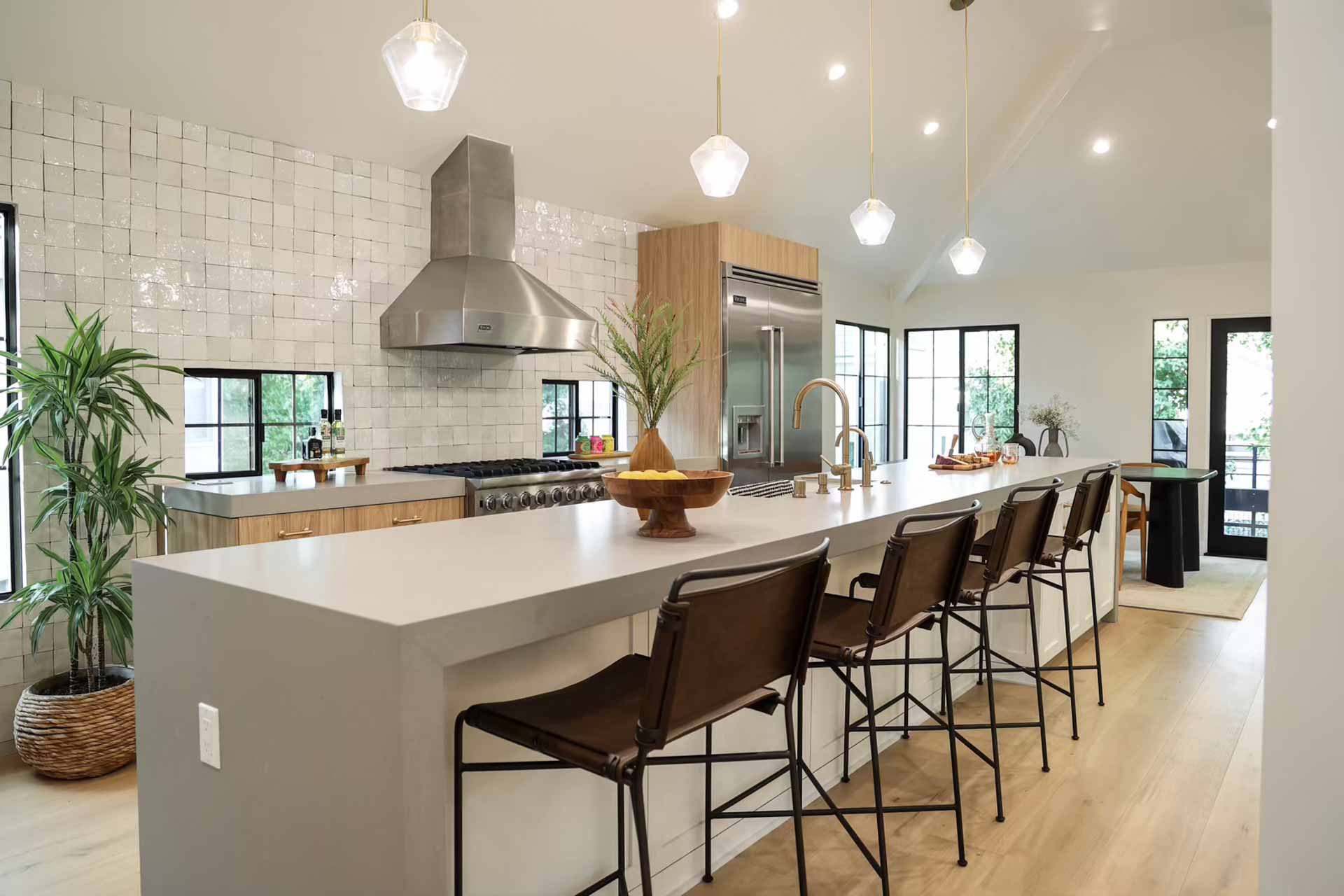 Modern kitchen remodel featuring white quartz waterfall island, zellige tile backsplash, leather bar stools, and pendant lighting - New Dawn Construction